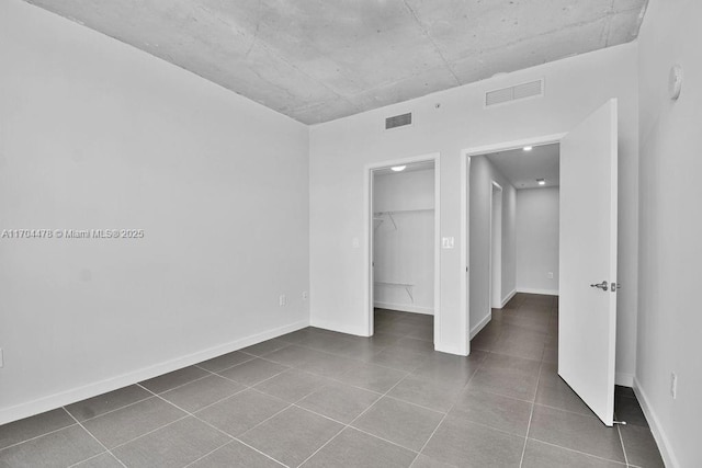 unfurnished bedroom featuring tile patterned flooring, a spacious closet, and a closet