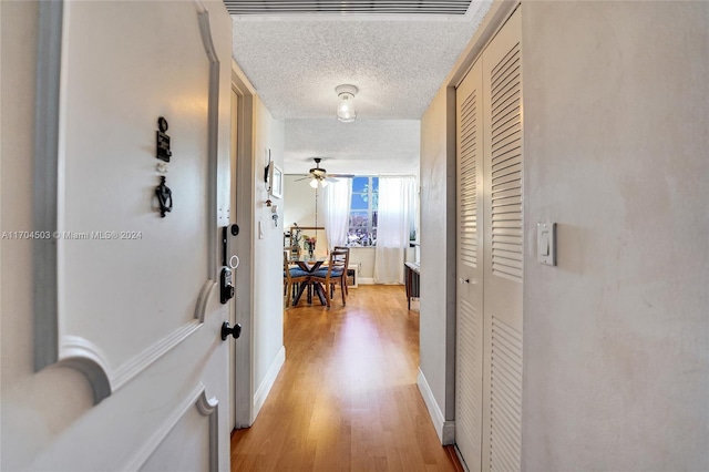 hallway featuring a textured ceiling and light hardwood / wood-style flooring