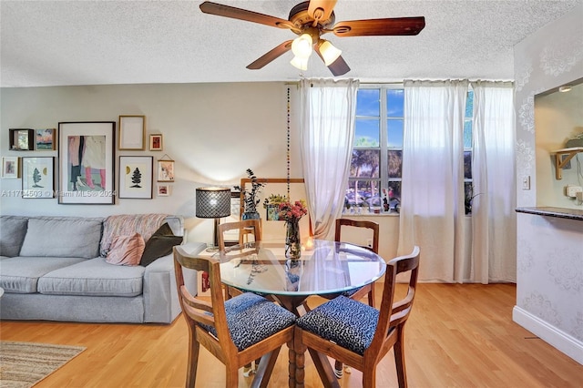 dining space with ceiling fan, light hardwood / wood-style floors, and a textured ceiling