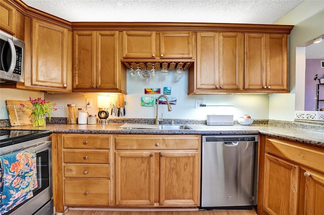 kitchen featuring sink, light wood-type flooring, a textured ceiling, and appliances with stainless steel finishes