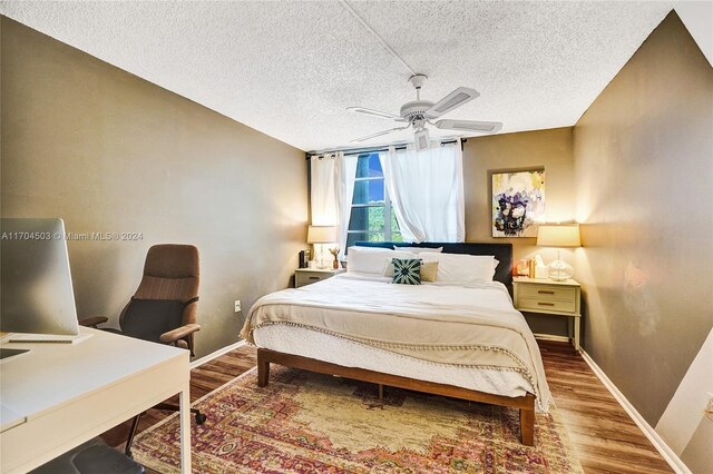 bedroom with ceiling fan, hardwood / wood-style floors, and a textured ceiling