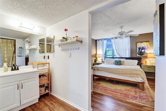 bedroom featuring ceiling fan, sink, wood-type flooring, and a textured ceiling