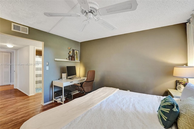 bedroom with wood-type flooring, a textured ceiling, and ceiling fan