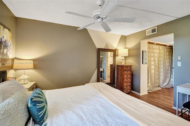 bedroom with ceiling fan, wood-type flooring, a textured ceiling, and lofted ceiling