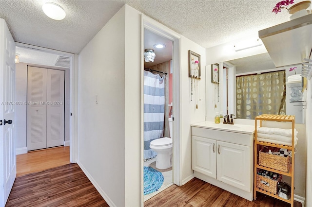 bathroom featuring hardwood / wood-style floors, vanity, toilet, and a textured ceiling