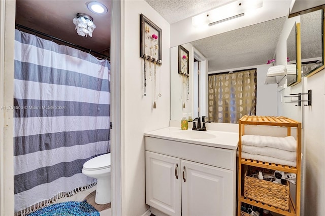 bathroom with vanity, toilet, and a textured ceiling