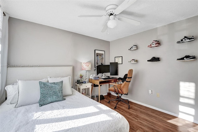 bedroom with hardwood / wood-style flooring, ceiling fan, and a textured ceiling