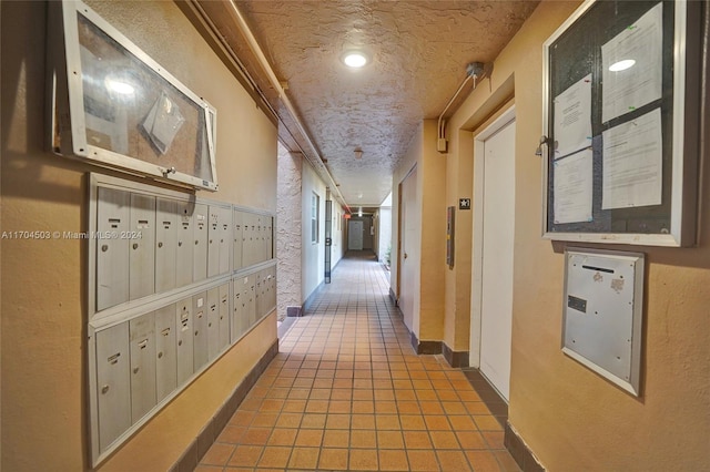 hallway featuring tile patterned floors, a mail area, and a textured ceiling