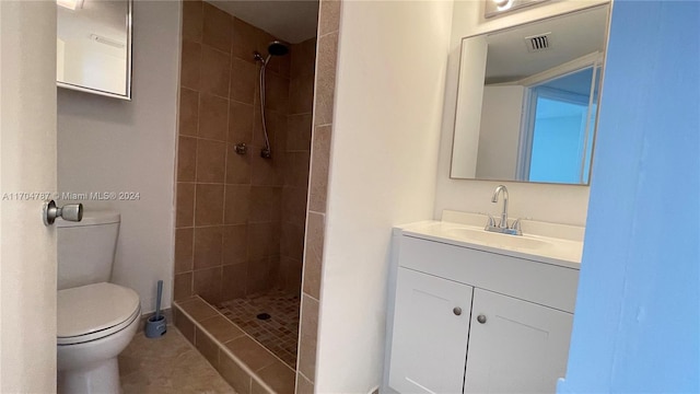 bathroom with tile patterned floors, vanity, toilet, and tiled shower