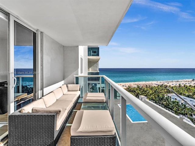 balcony with an outdoor living space, a water view, and a beach view