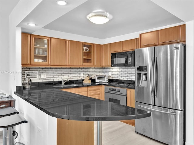 kitchen with a kitchen bar, kitchen peninsula, sink, and appliances with stainless steel finishes