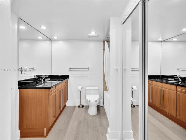 full bathroom featuring vanity, hardwood / wood-style flooring, toilet, and  shower combination