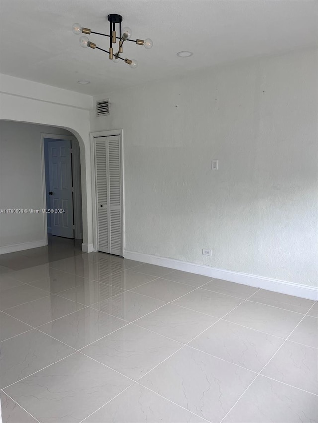 unfurnished room featuring tile patterned flooring and an inviting chandelier