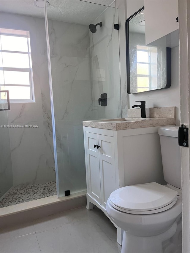 bathroom with vanity, toilet, a shower with shower door, and a textured ceiling