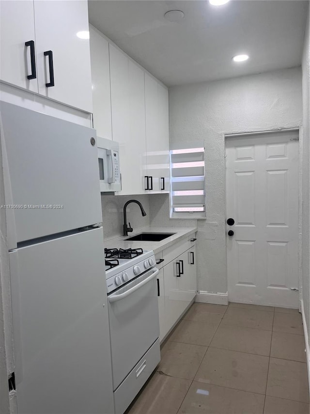 kitchen featuring decorative backsplash, white appliances, sink, white cabinetry, and light tile patterned flooring