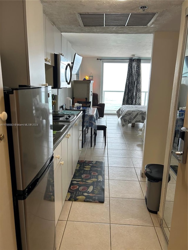 kitchen with light tile patterned flooring, white cabinetry, and appliances with stainless steel finishes