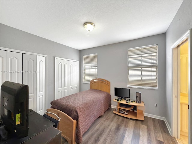 bedroom featuring a textured ceiling, hardwood / wood-style flooring, and multiple closets