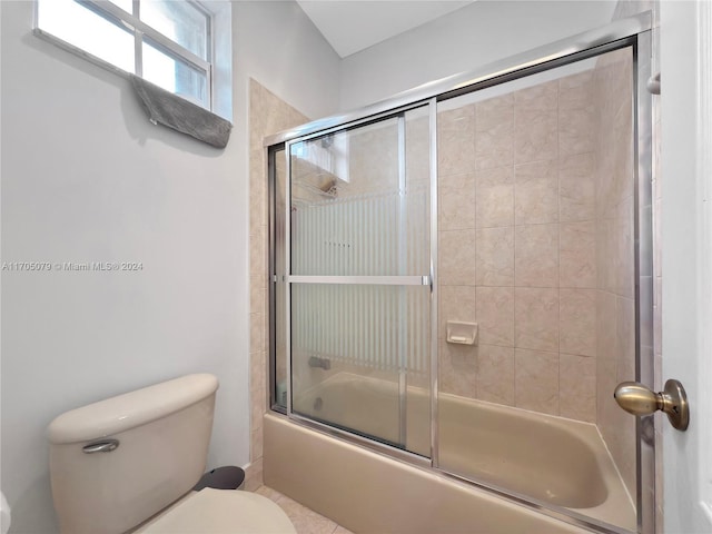 bathroom featuring combined bath / shower with glass door and toilet