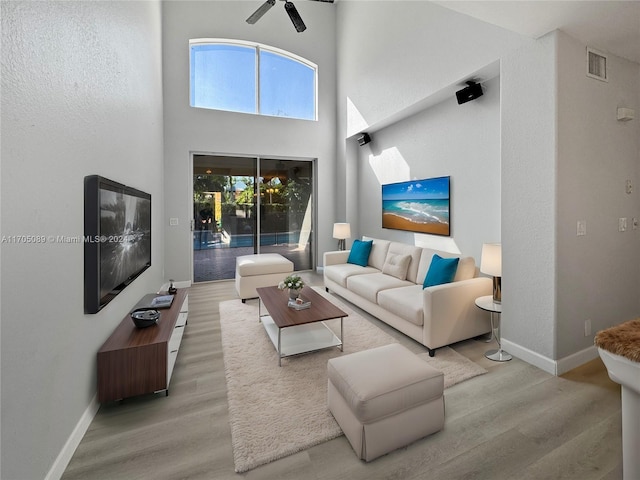 living room with a high ceiling, hardwood / wood-style flooring, and ceiling fan