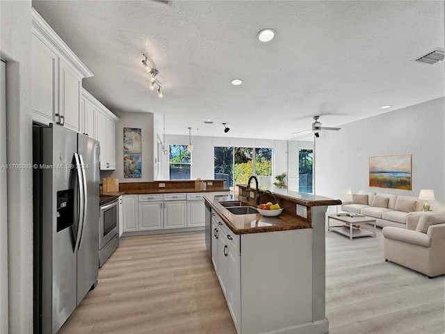 kitchen featuring white cabinetry, sink, a textured ceiling, appliances with stainless steel finishes, and light wood-type flooring