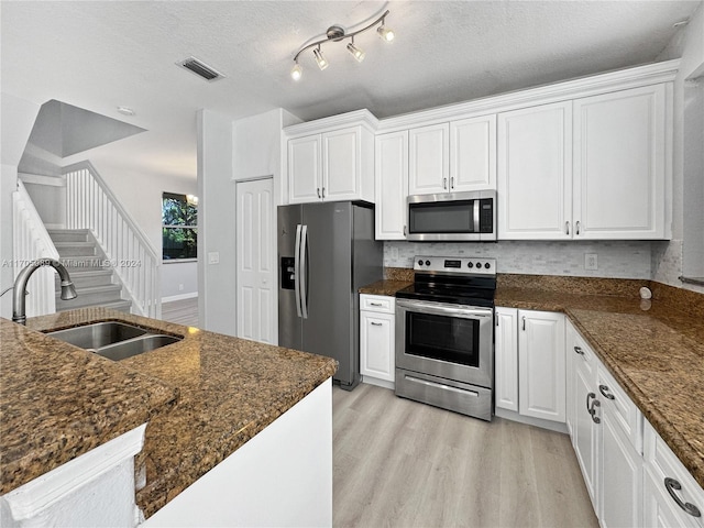 kitchen with a textured ceiling, sink, white cabinetry, and stainless steel appliances