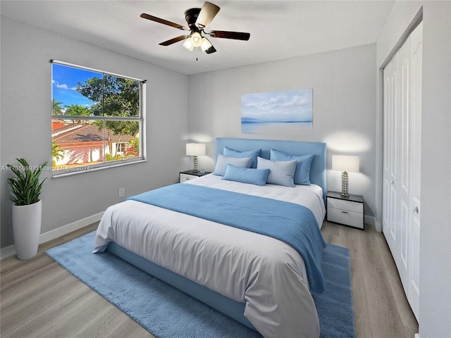 bedroom with a closet, light hardwood / wood-style floors, and ceiling fan