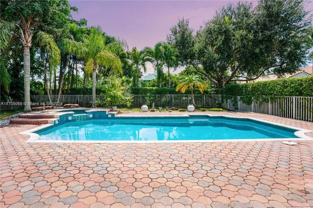 pool at dusk featuring a patio