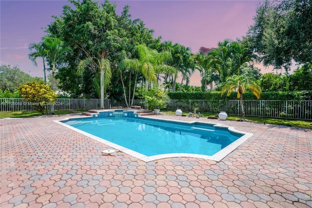 pool at dusk with a patio area