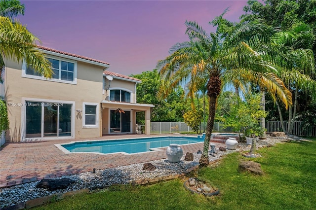 pool at dusk featuring a yard and a patio area