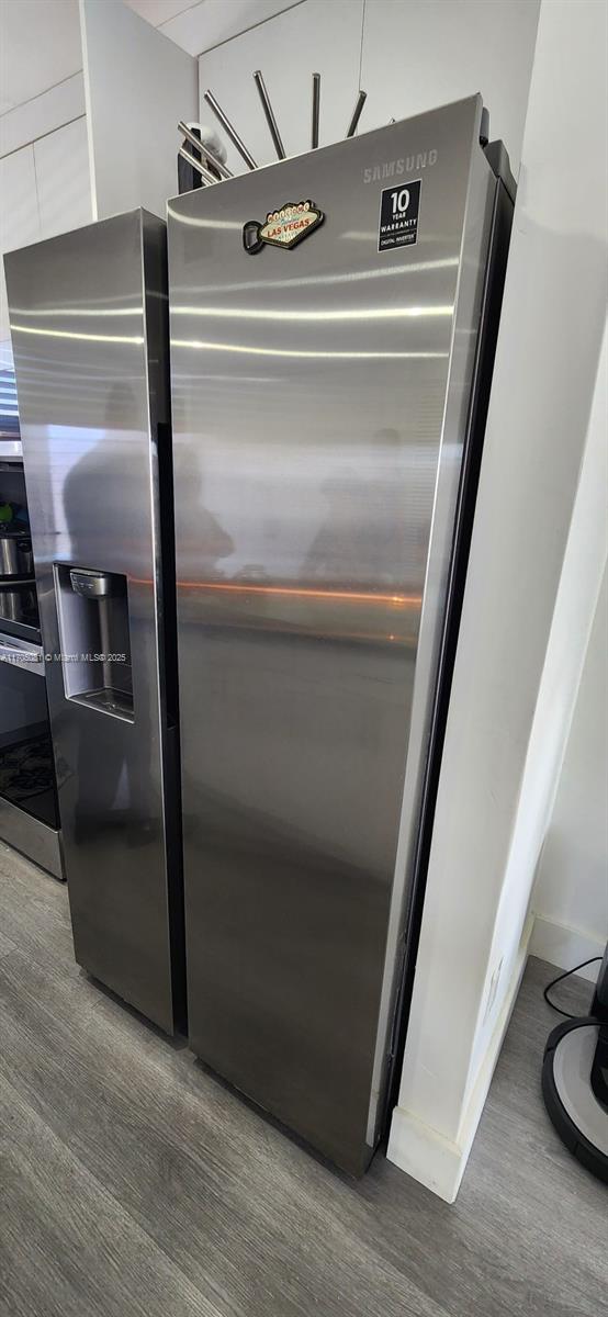 room details featuring oven, wood finished floors, and freestanding refrigerator