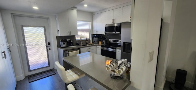 kitchen with a kitchen breakfast bar, sink, decorative backsplash, white cabinetry, and stainless steel appliances