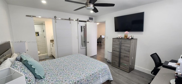 bedroom featuring a barn door, ceiling fan, hardwood / wood-style floors, and ensuite bath