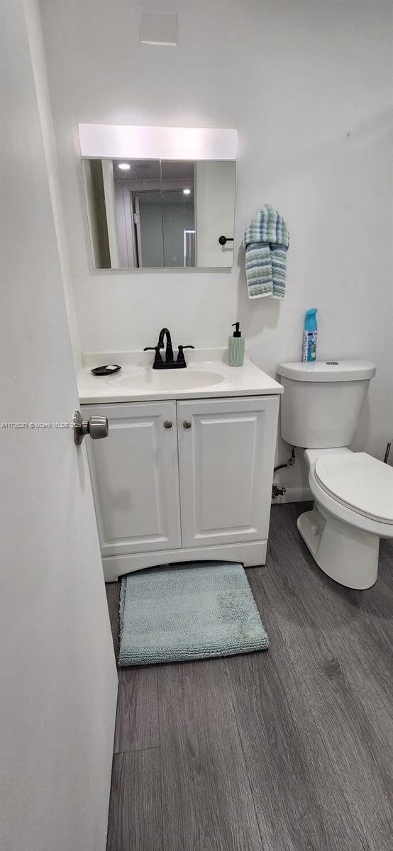 half bath featuring vanity, wood finished floors, and toilet