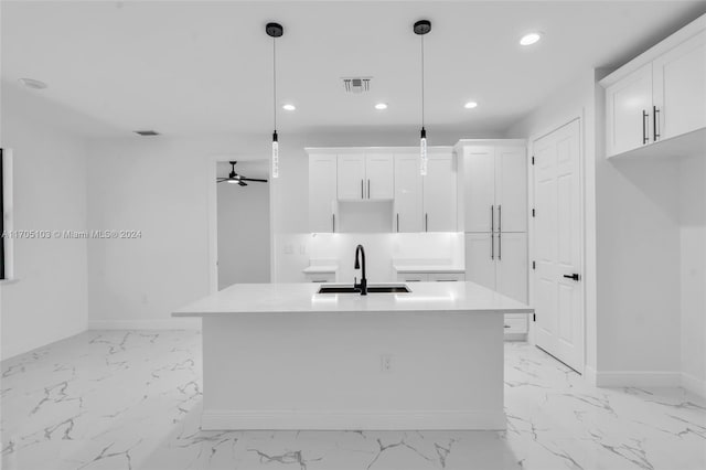 kitchen with white cabinets, sink, ceiling fan, an island with sink, and decorative light fixtures