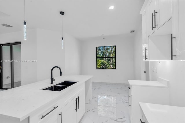 kitchen with white cabinets, pendant lighting, sink, and a kitchen island with sink