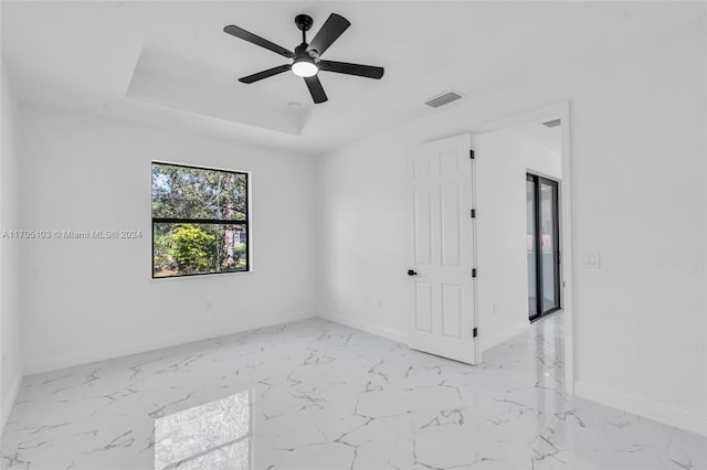 empty room with a tray ceiling and ceiling fan