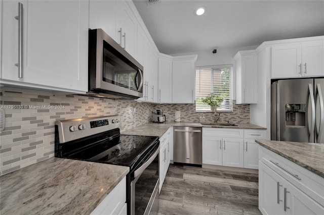 kitchen featuring white cabinetry, sink, stainless steel appliances, tasteful backsplash, and hardwood / wood-style floors