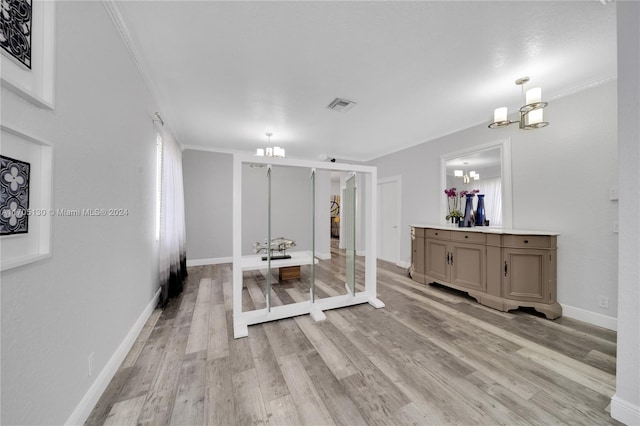 living room with light hardwood / wood-style floors, an inviting chandelier, and ornamental molding