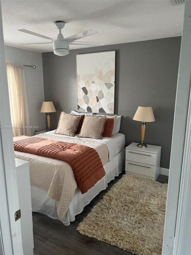 bedroom with a textured ceiling, ceiling fan, and dark wood-type flooring