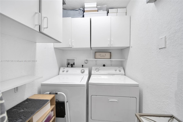 laundry room featuring washer and dryer, cabinets, and a textured ceiling