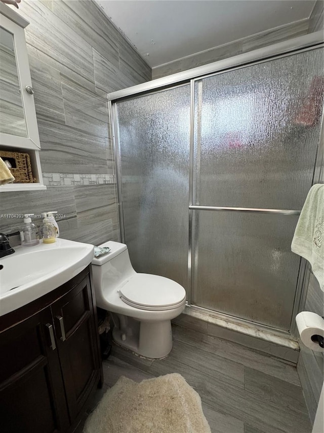 bathroom featuring vanity, an enclosed shower, tile walls, and toilet