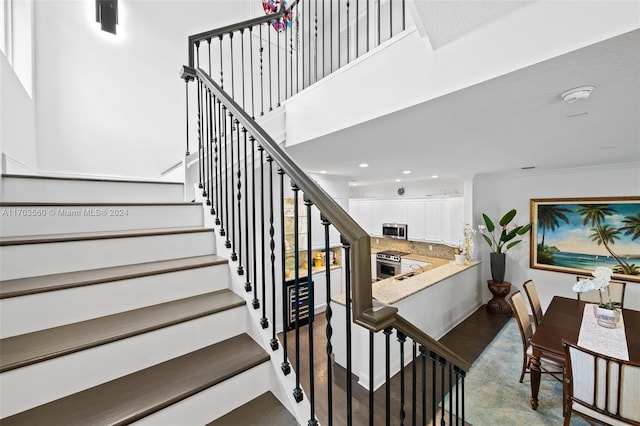 staircase featuring hardwood / wood-style flooring, sink, and crown molding