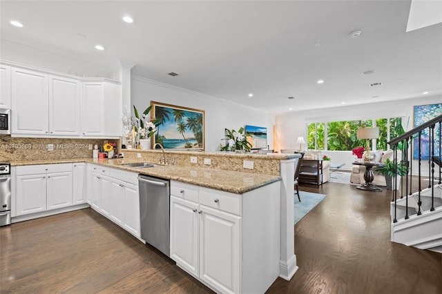 kitchen with sink, dark hardwood / wood-style floors, kitchen peninsula, white cabinets, and appliances with stainless steel finishes