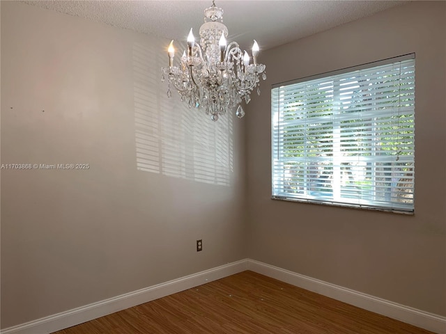 unfurnished room with a chandelier, a textured ceiling, and hardwood / wood-style flooring