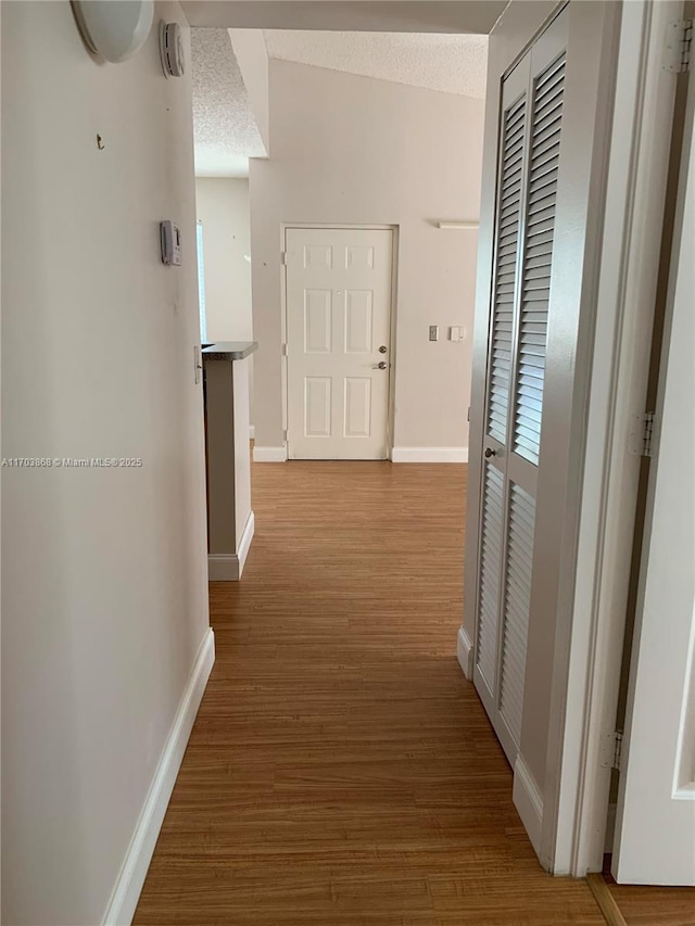 corridor featuring wood-type flooring and a textured ceiling