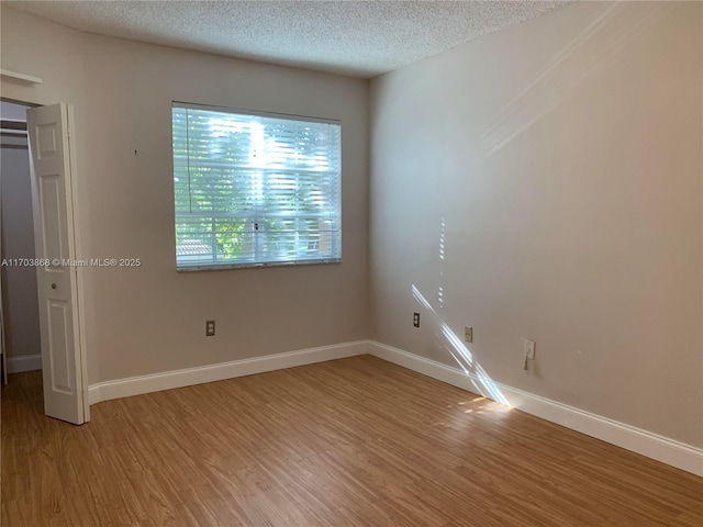 unfurnished room featuring hardwood / wood-style flooring and a textured ceiling