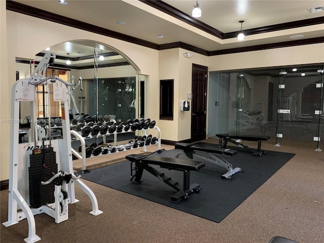 gym featuring a raised ceiling and crown molding