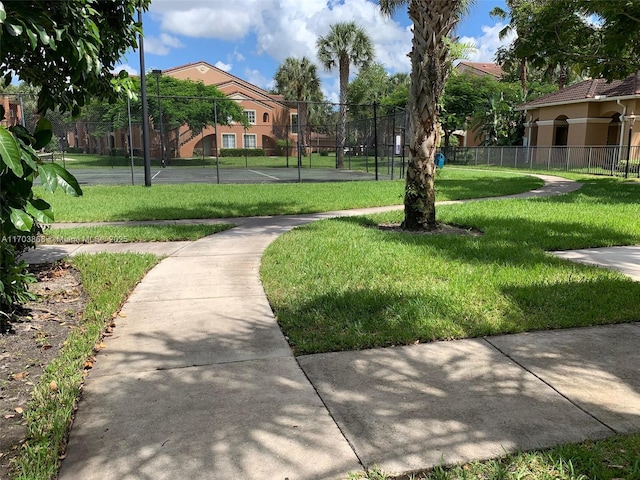 view of community with tennis court and a yard