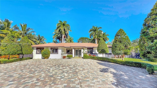 single story home with fence, stucco siding, a tile roof, and french doors