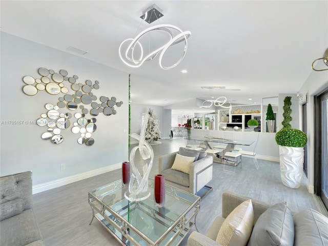 living area featuring an inviting chandelier, baseboards, vaulted ceiling, and wood finished floors